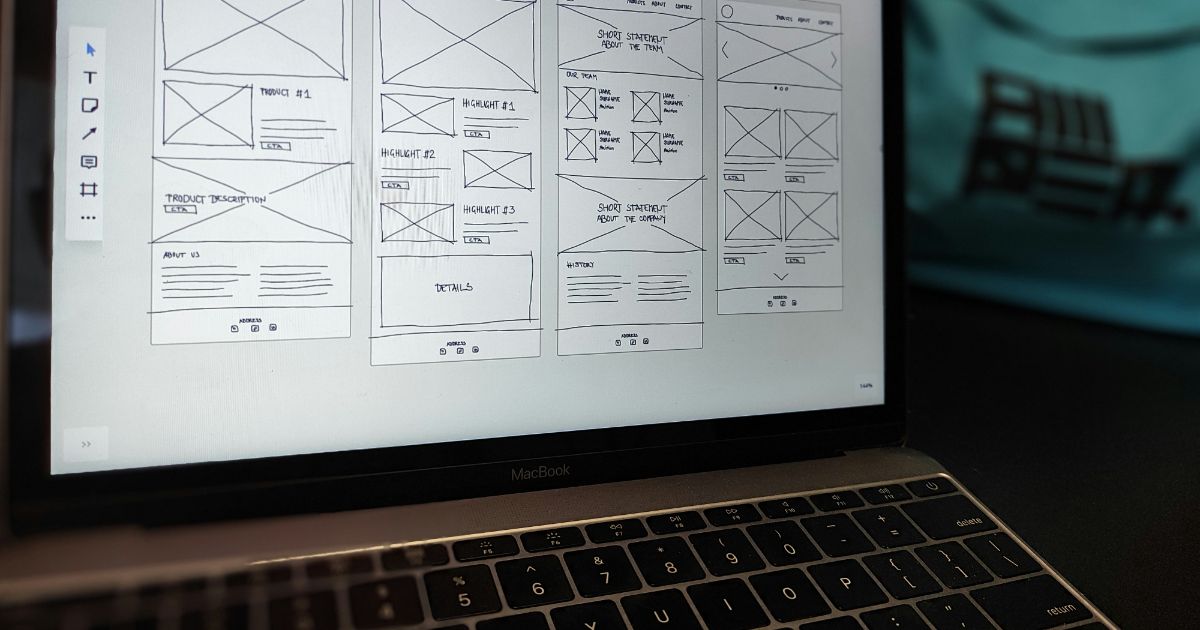 Laptop screen displaying black-and-white wireframe sketches of webpage layouts.