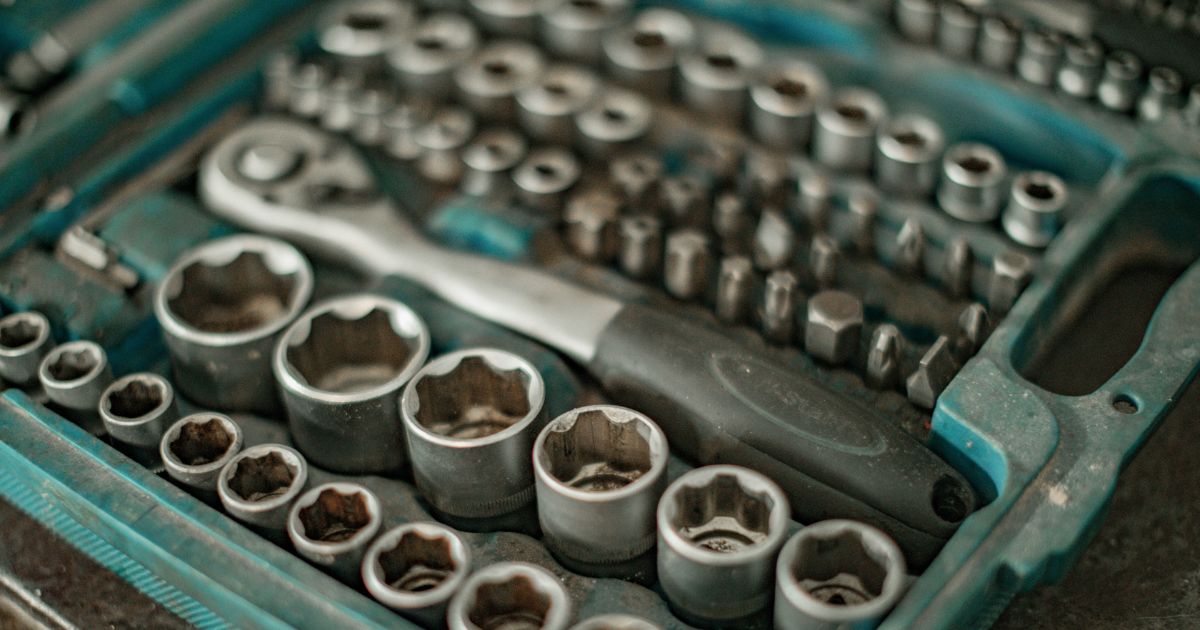 Close-up of a toolset in a teal plastic case with a ratchet wrench and various socket pieces.