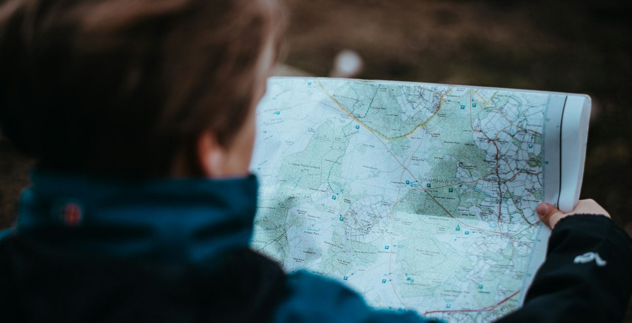 A child exploring the woods, excitedly holding a map, embodying curiosity and adventure in nature.