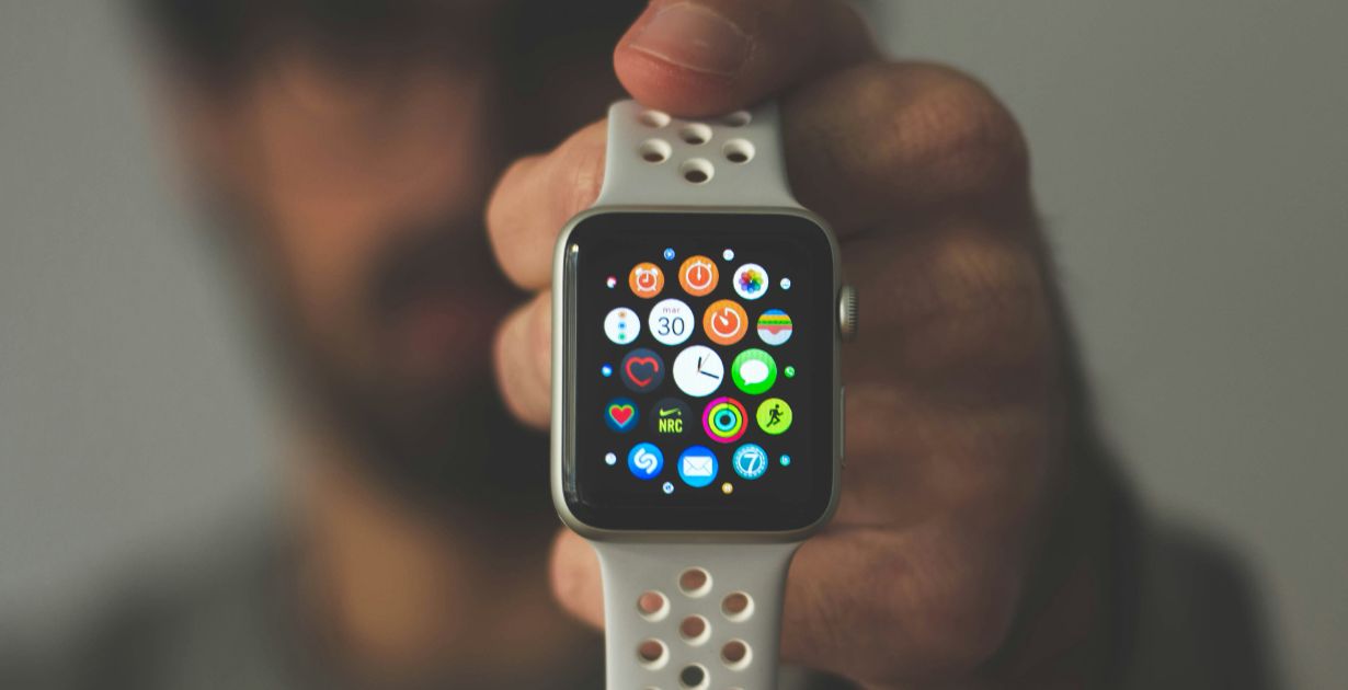 A person showcasing an Apple Watch displaying various app icons, highlighting user experience design features representing adapt UX for new interfaces.