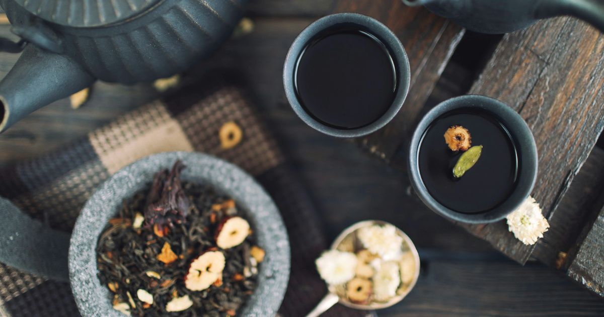 A wooden table displaying a cup of tea and a cup of black tea, highlighting their distinct colors and textures.
