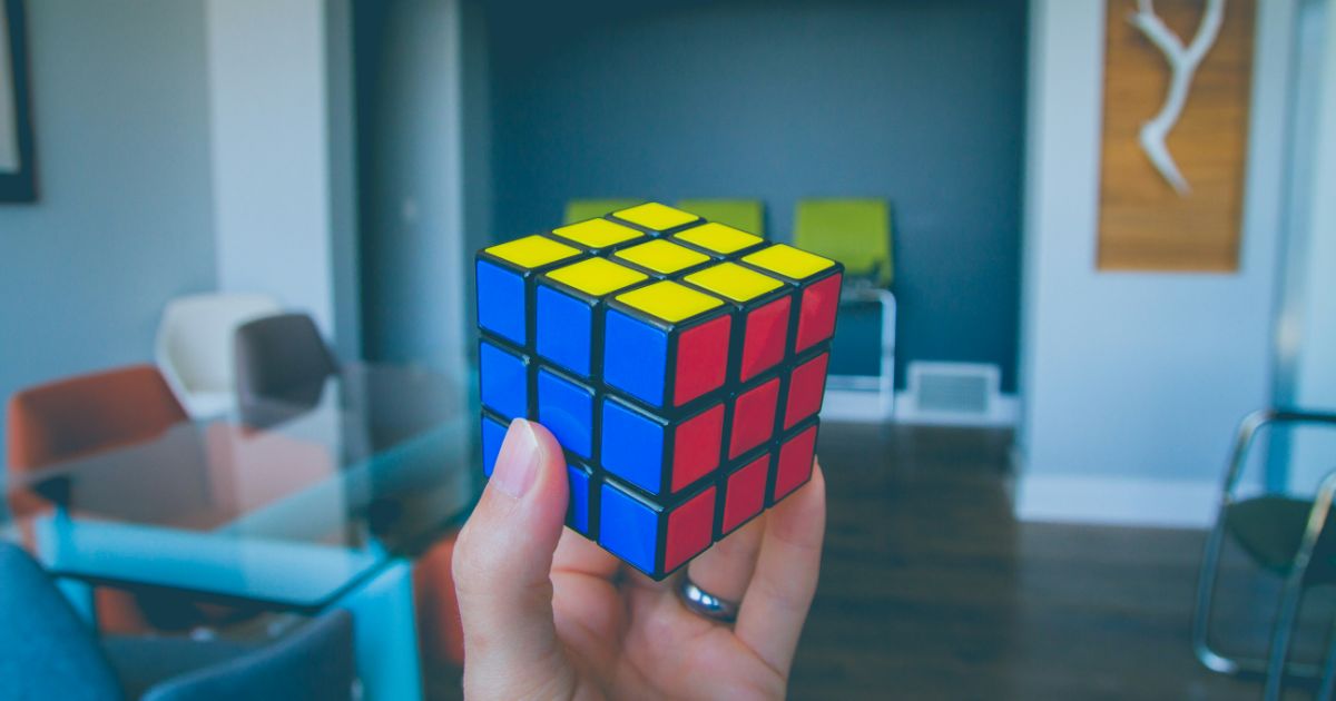 Hand holding a solved Rubik's Cube in a modern interior space.
