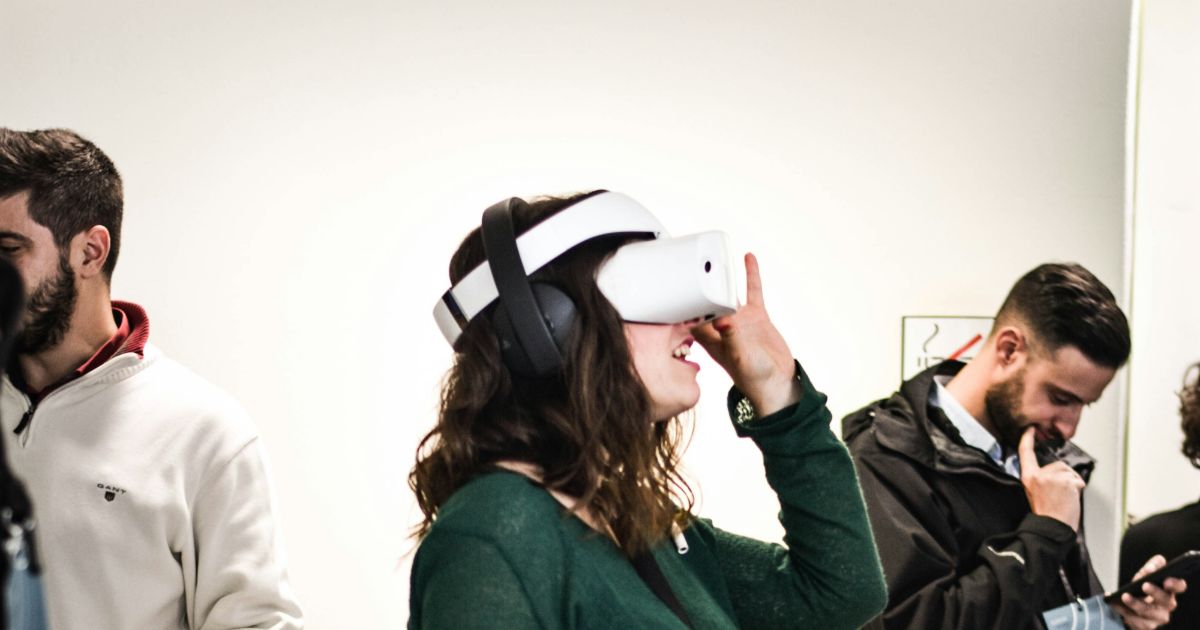 People in a room, one using a virtual reality headset.