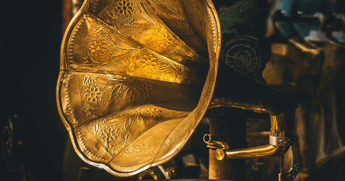 Close-up of a golden gramophone horn with floral patterns.