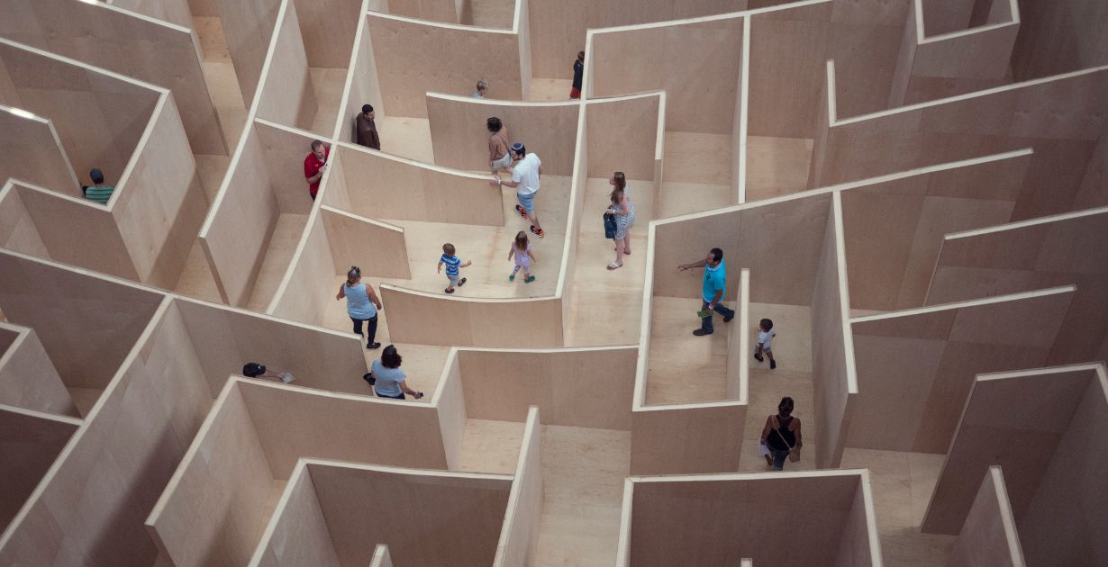 People navigate a maze of wooden boxes, illustrating the complexities of user experience design in a playful setting.