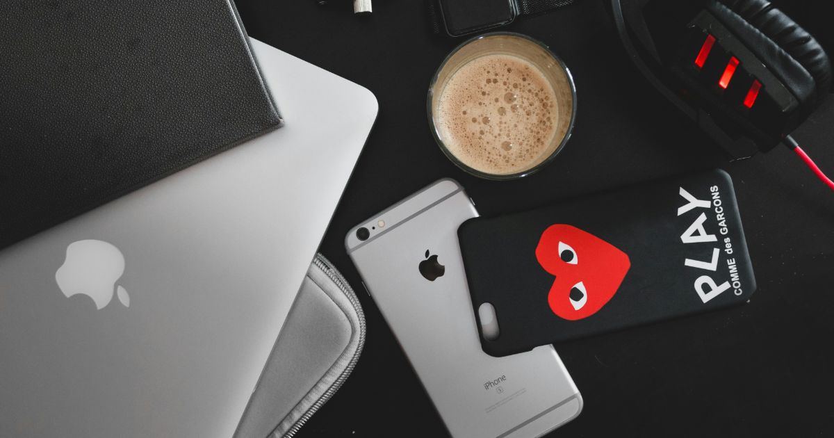 laptop, coffee cup, and iPhone on a table, showcasing a modern workspace for the 5G UX Revolution.