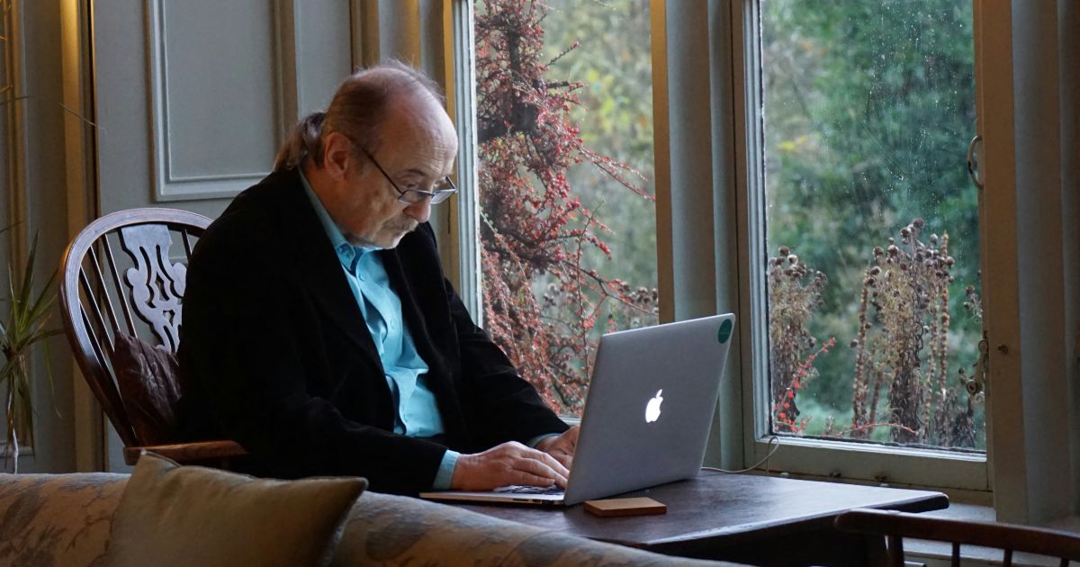 A man seated in a chair, using a laptop, exemplifying accessible technology for older adults.