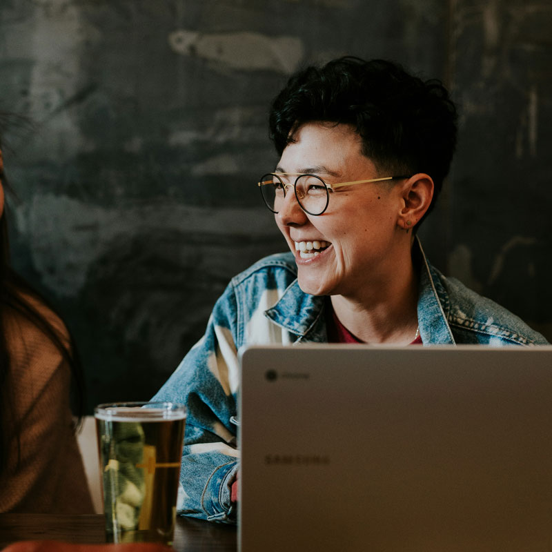 brooke-cagle-nuyCCp8jleU-unsplash A women engaged in conversation at a table, working together on a laptop.