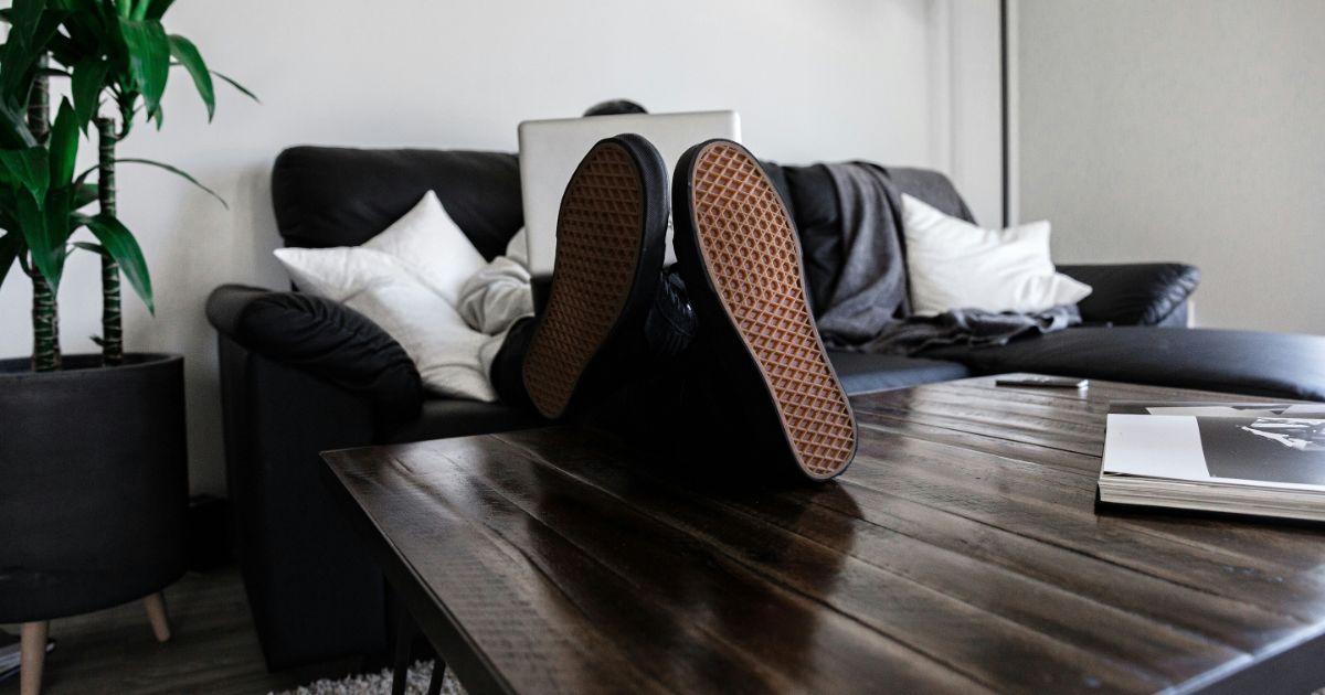 A person comfortably seated on a couch, feet resting on a table, engaged in remote UX research.