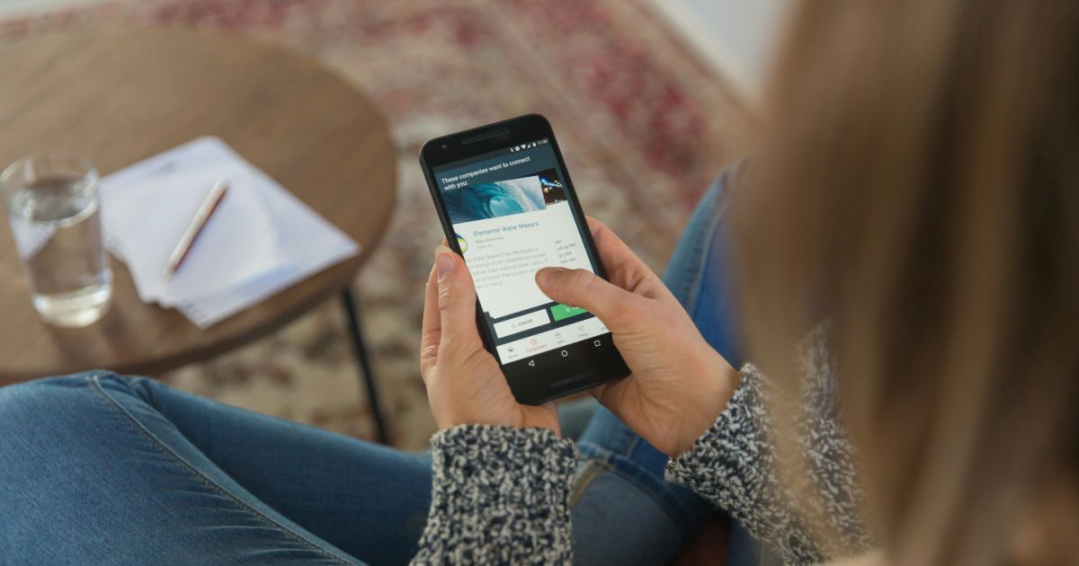 A person using a mobile smart phone in a cozy setting.