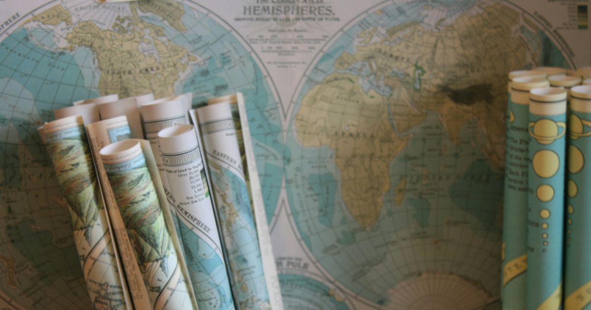 Rolled maps in front of a two-hemisphere world map.