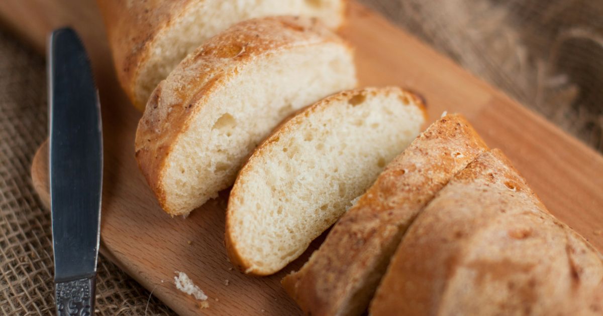 Freshly baked bread resting on a wooden cutting board beside a sharp knife, ready to be sliced and enjoyed.