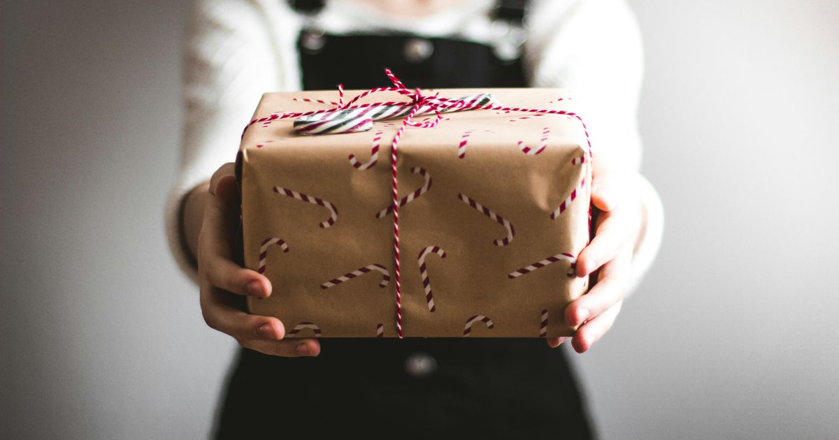A person joyfully holding a beautifully wrapped gift box, symbolizing the spirit of giving and reciprocity in ux.