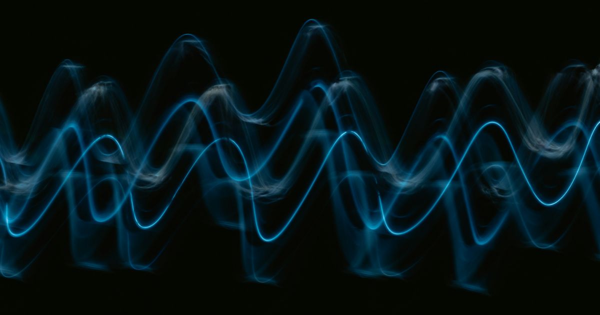 A vibrant blue wave of sound waves undulates against a sleek black background, symbolizing quantum computing and UX innovation.