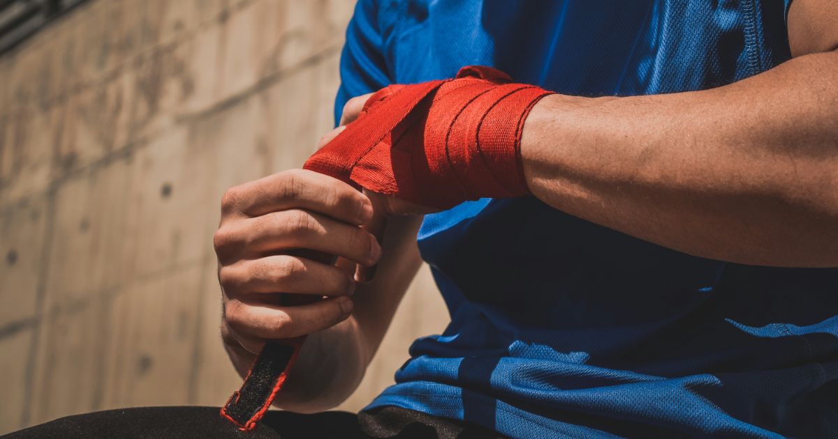 A man with red bandages on his hands, symbolizing resilience and adaptation in the face of temporary disabilities.