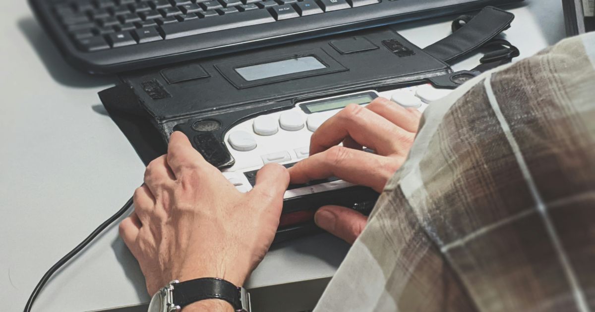 A person operates a remote control to manage a computer, illustrating Sensory Inclusive Design in UX.