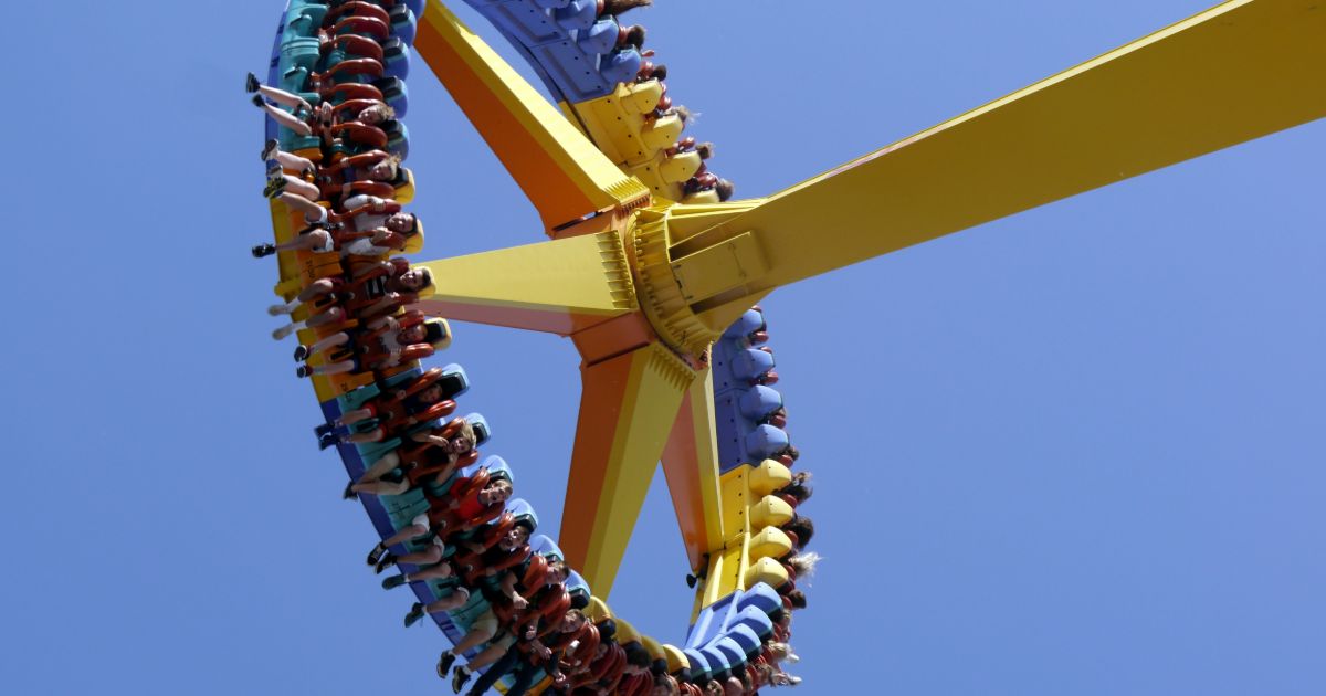 A thrilling roller coaster with excited riders soaring through the air on a sunny day representing a UX research flywheel.