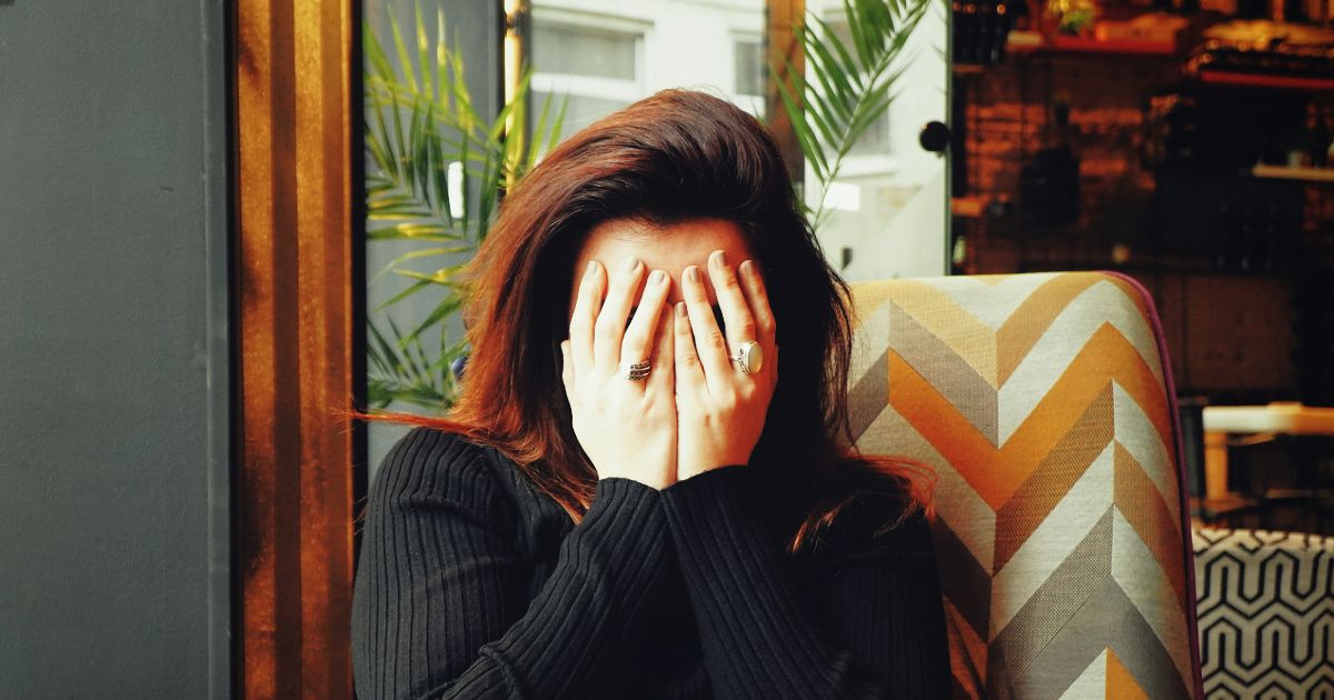 A woman covering her face with her hands, expressing emotions of distress or contemplation representing UX design and user shame.