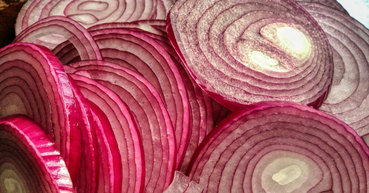 A vibrant pile of sliced red onions, showcasing their rich color and layered texture representing progressive disclosure.