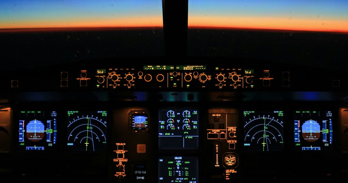 The cockpit of an airplane at dusk, illuminated by the warm glow of a sunset outside the windows representing ethics of AI in UX.
