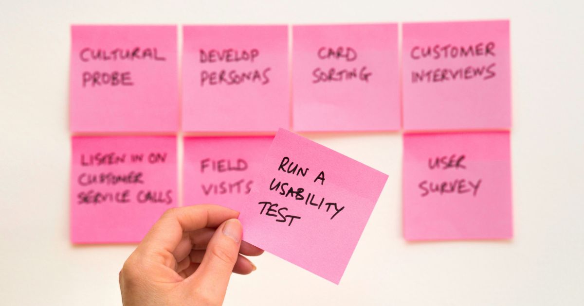 A person holds a piece of paper covered in colorful sticky notes, showcasing ideas or reminders representing UX research operations.