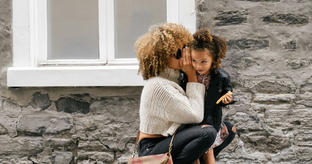 A woman and her daughter sit together on the ground, sharing a moment of connection and joy representing AI taxonomy generation.