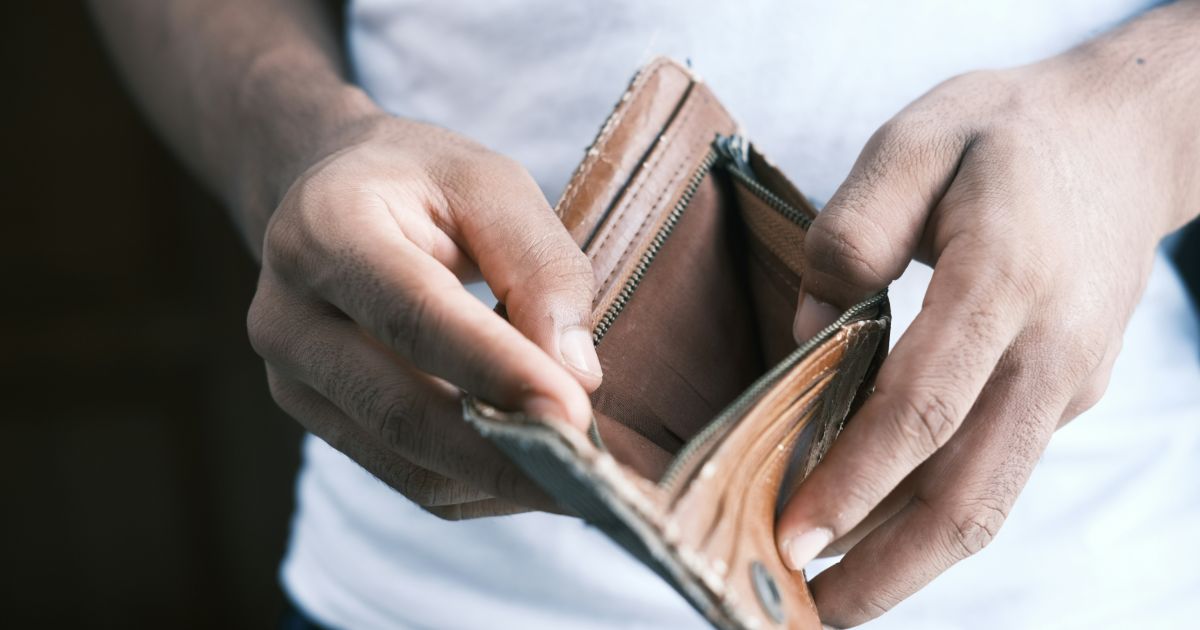 A man holds an empty wallet, looking disappointed and concerned about his financial situation representing UX research debt.