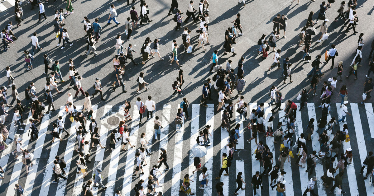 Aerial view of diverse people walking across a busy street, illustrating Imperfect personas in UX.