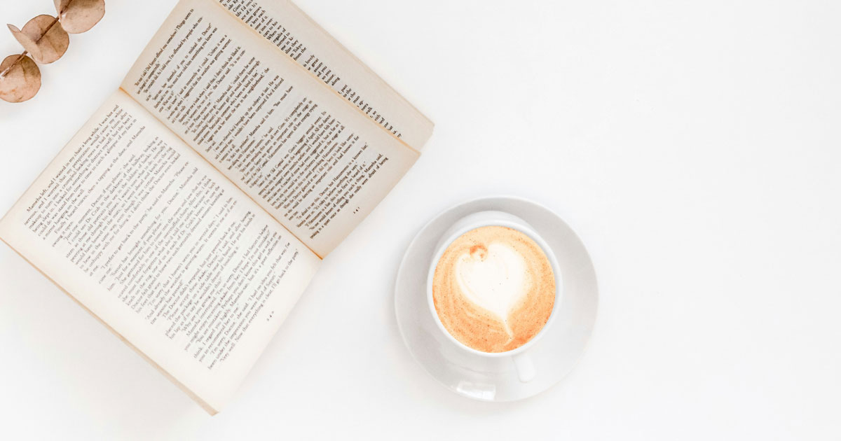 A cup of coffee beside an open book on a white background, illustrating the concept of whitespace in UX design.